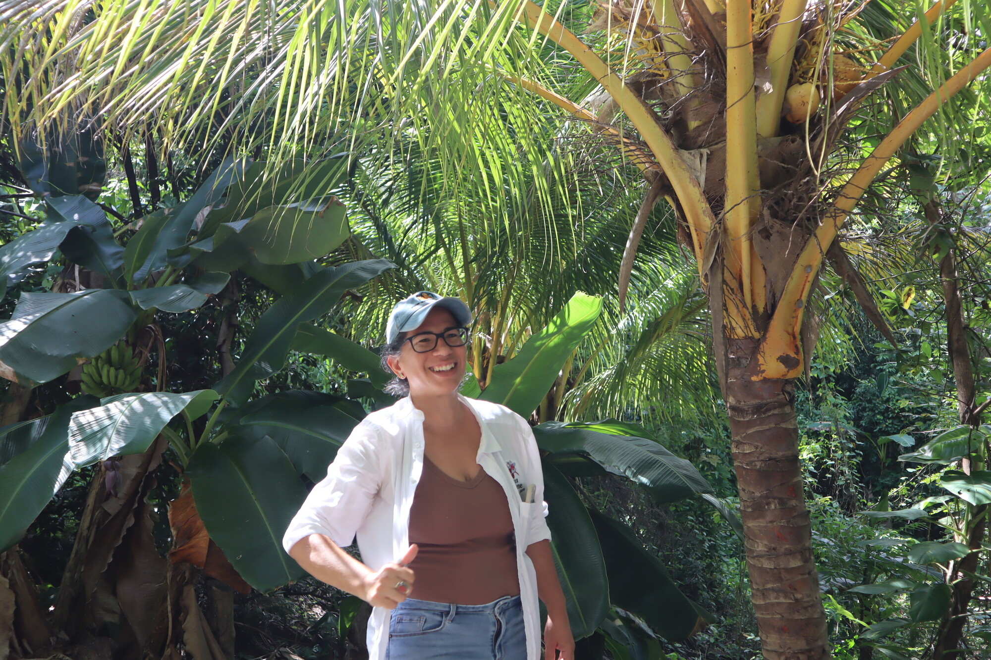 A woman standing in front of lush green trees