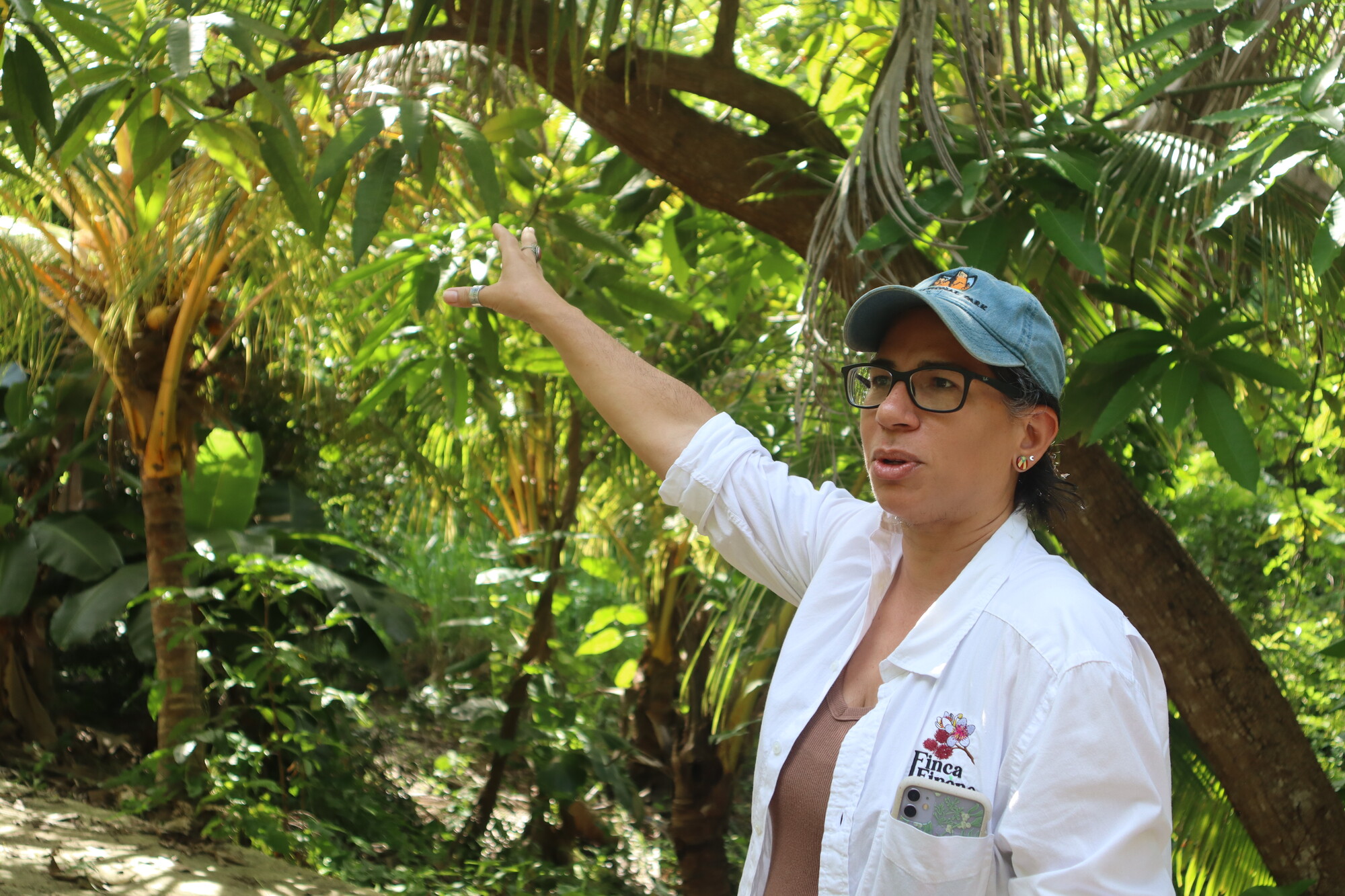 A woman gesturing to lush trees in a forest