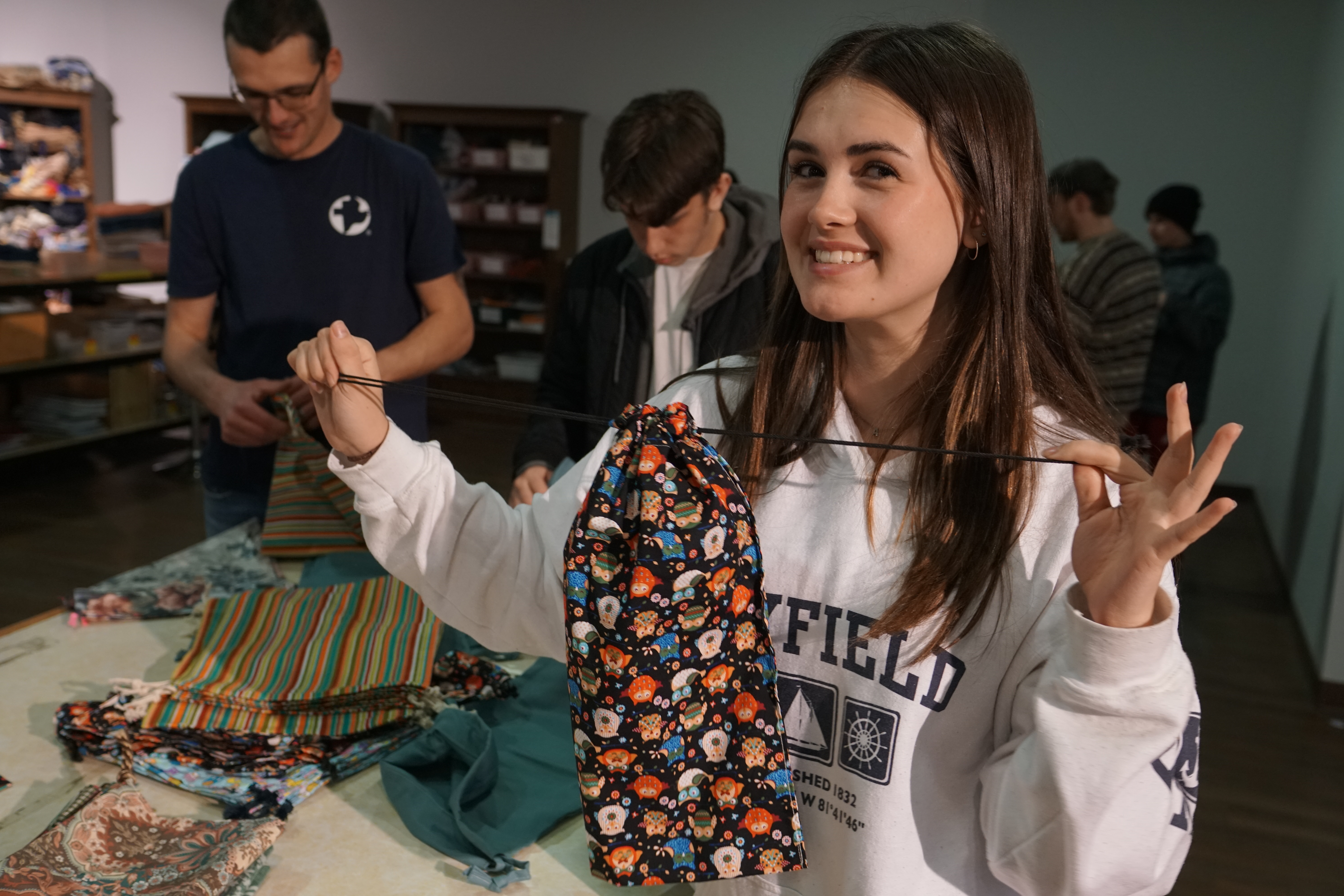 smiling woman holds up hygiene kit bag