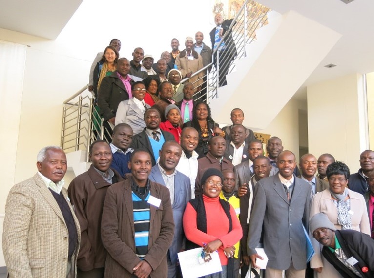 About three dozen people stand together on a stairwell facing the camera.