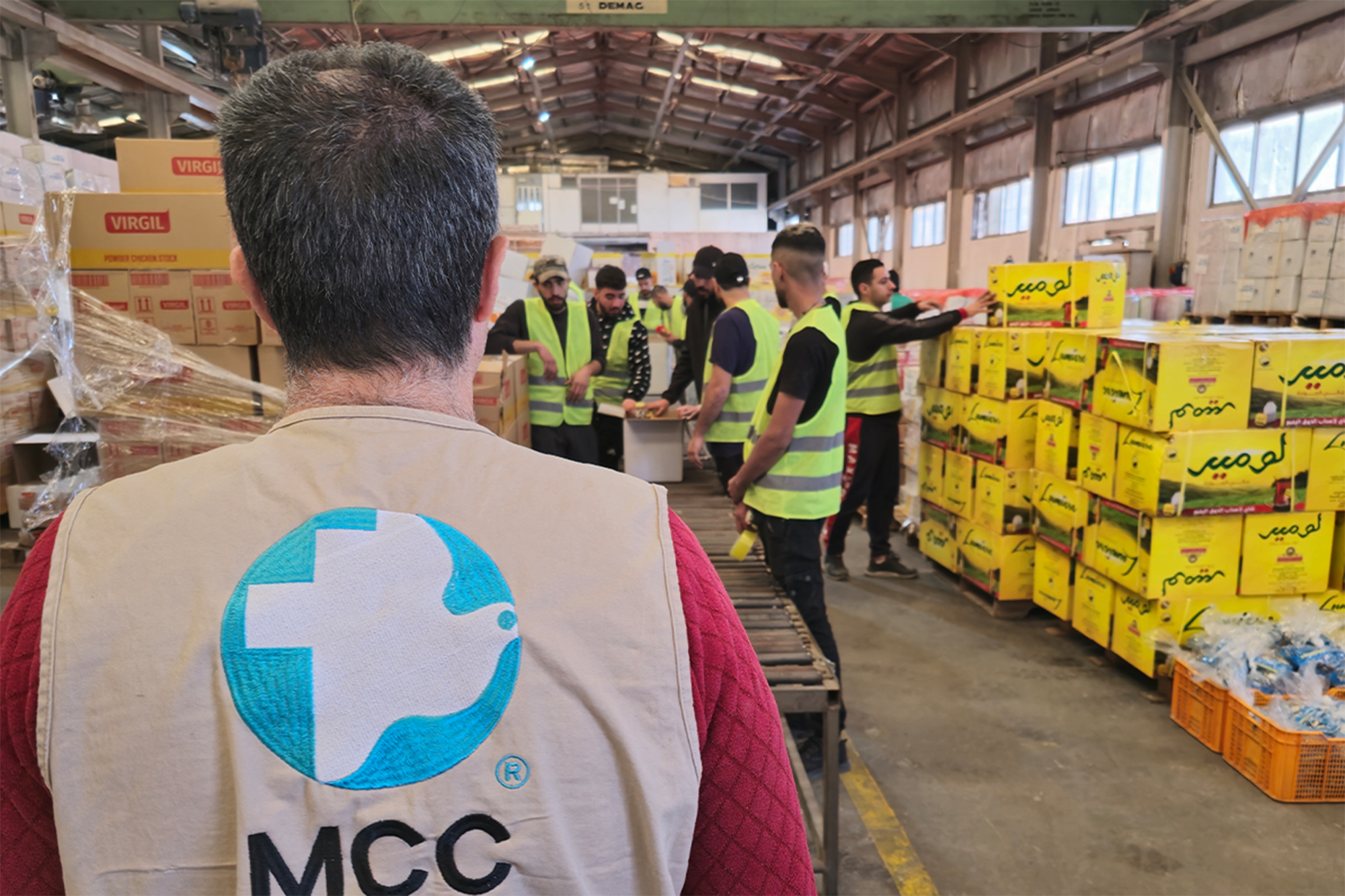 An MCC staff member observes workers packing emergency food packages in Amman, Jordan.