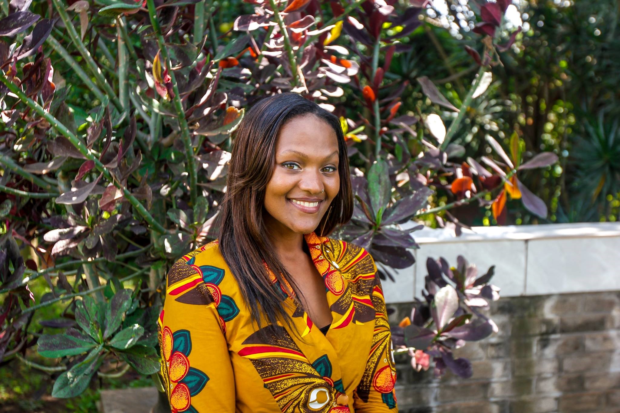 a young black woman in a yellow shirt smiles at the camera