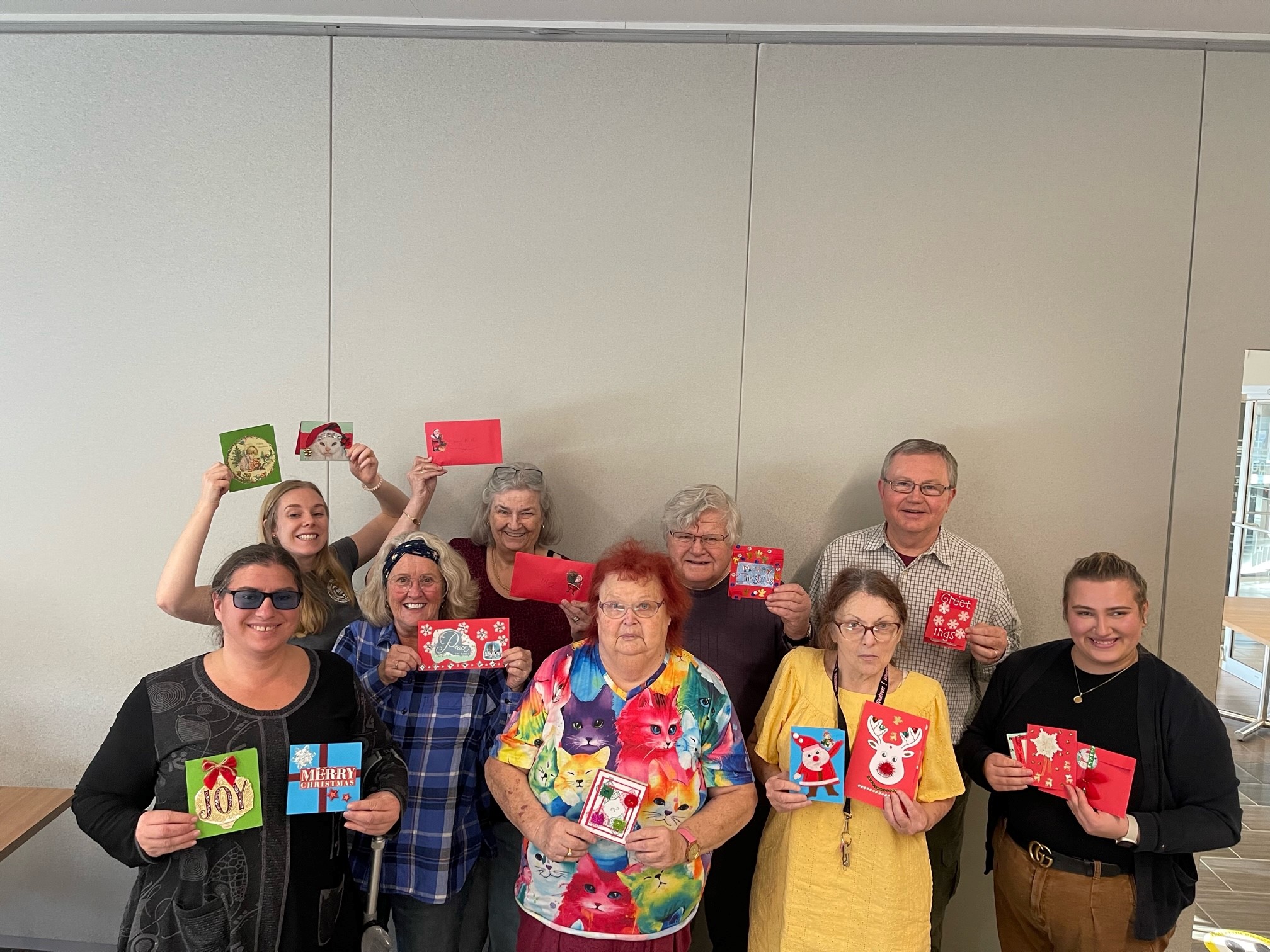 9 people hold up Christmas card that they made