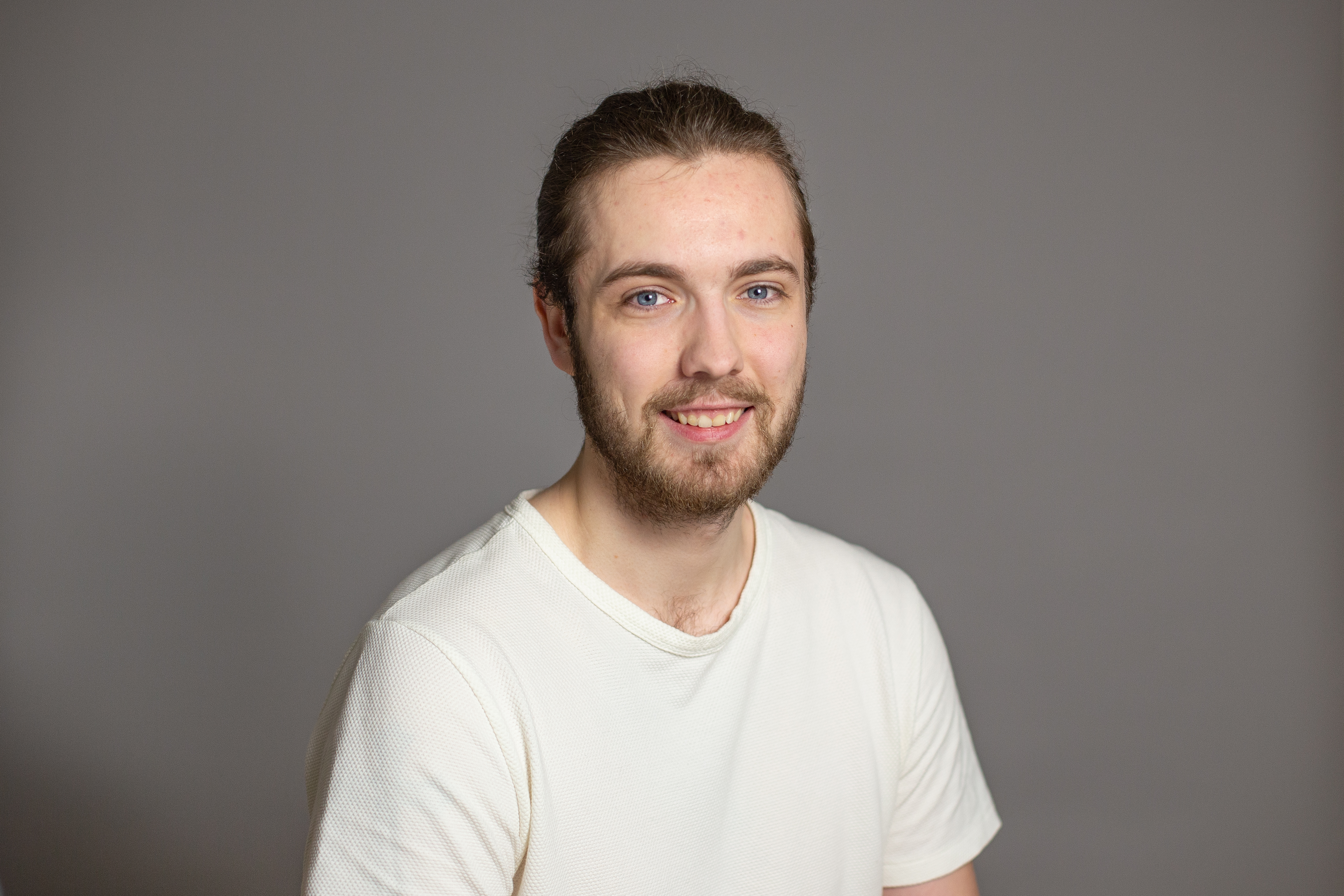 Brett Van Bergen, smiling in front of a grey backdrop.