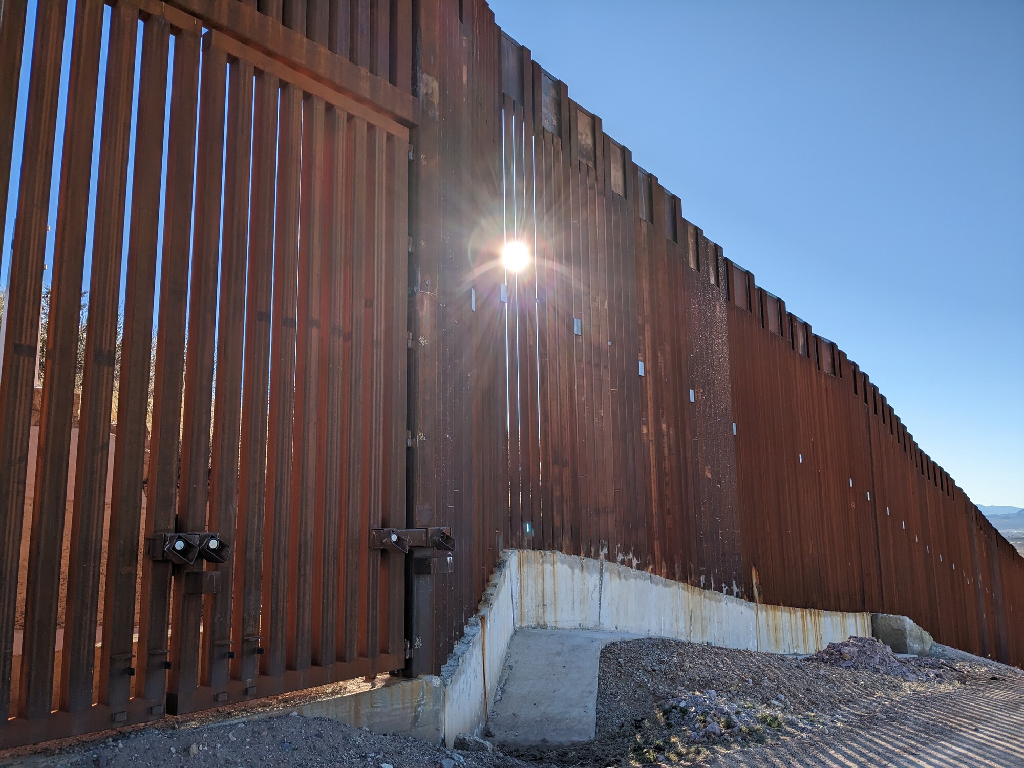 The sun shining through the tall, rusting border wall from Agua Prieta, Mexico into Douglas, Arizona.