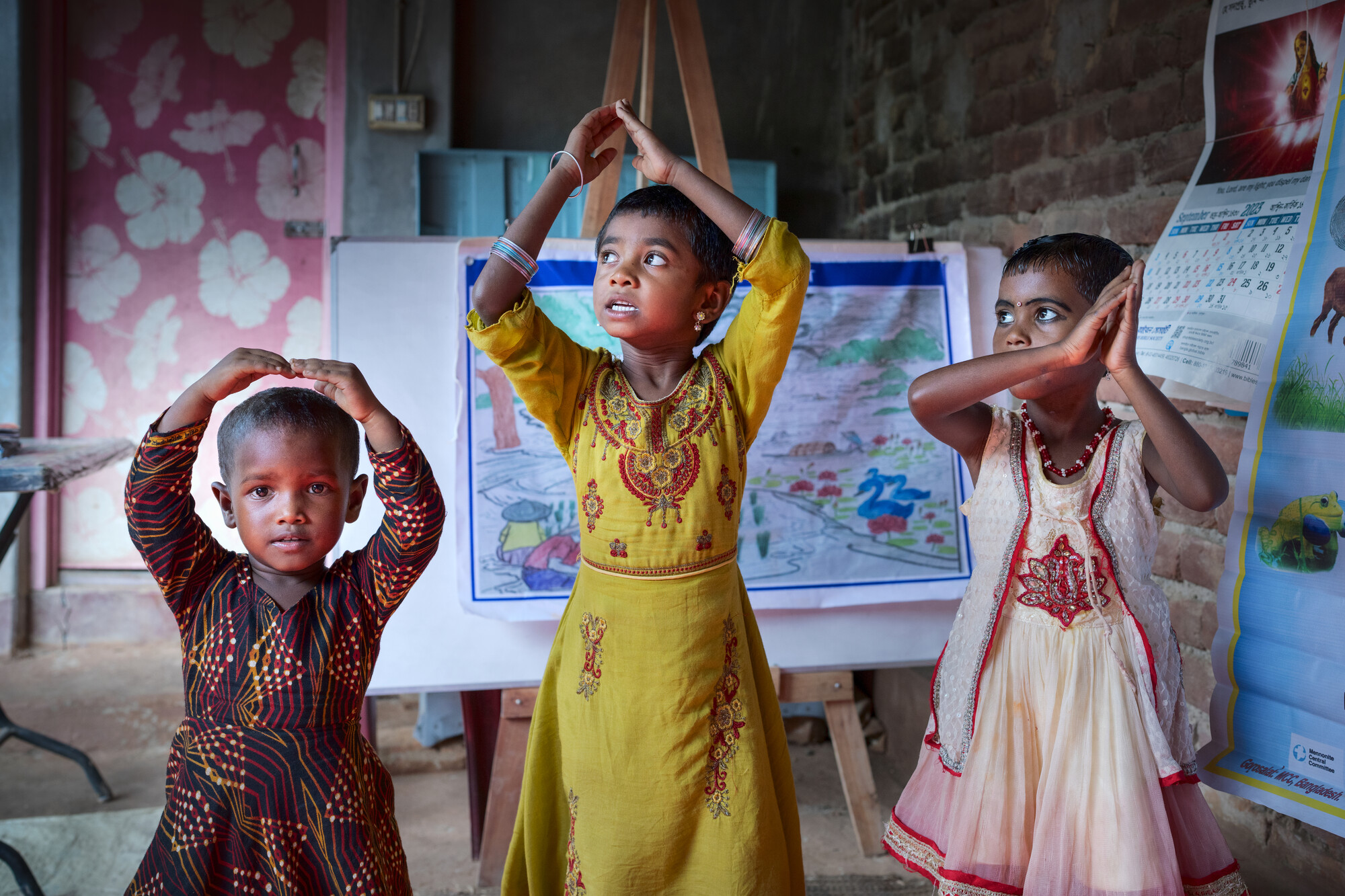 Three children stand with their arms upraised.