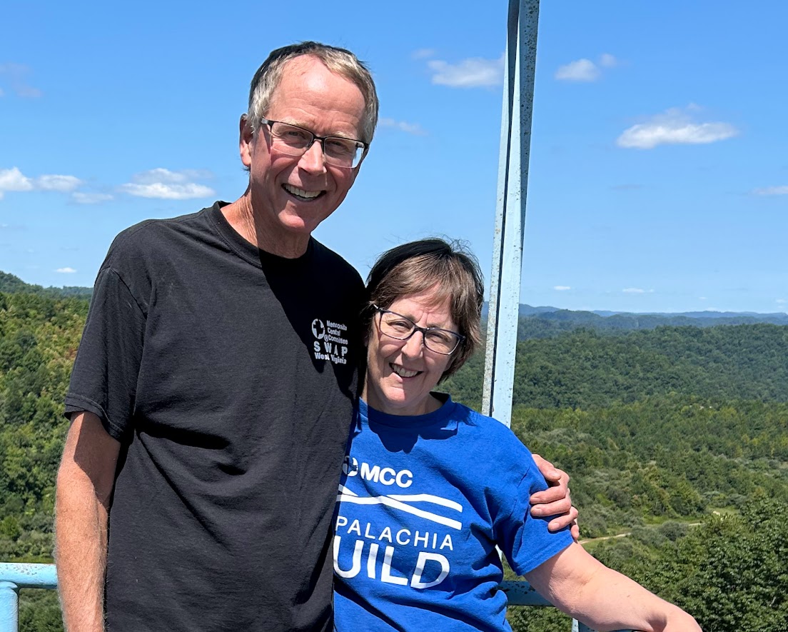 two people pose for a photo with mountains in the background