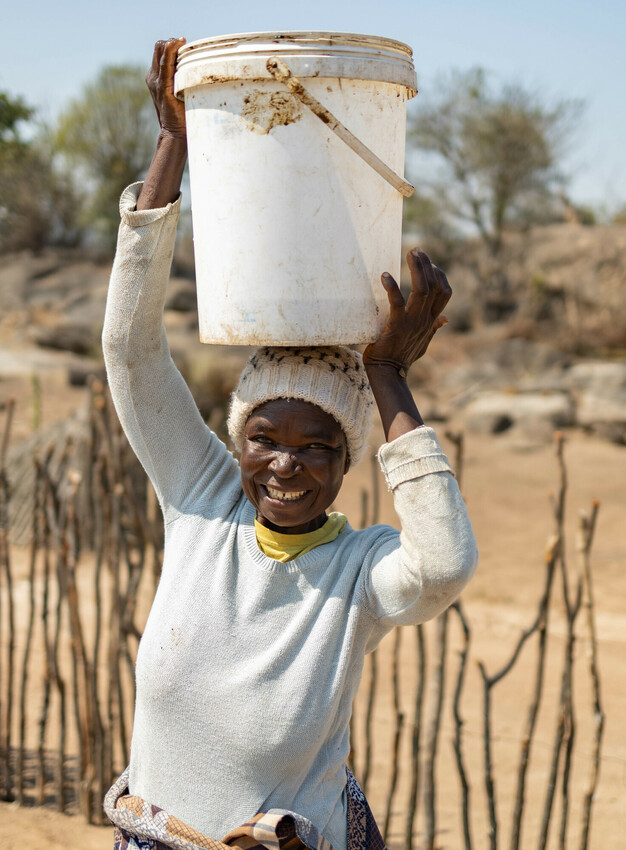 Lady carrying a bucket over her head.