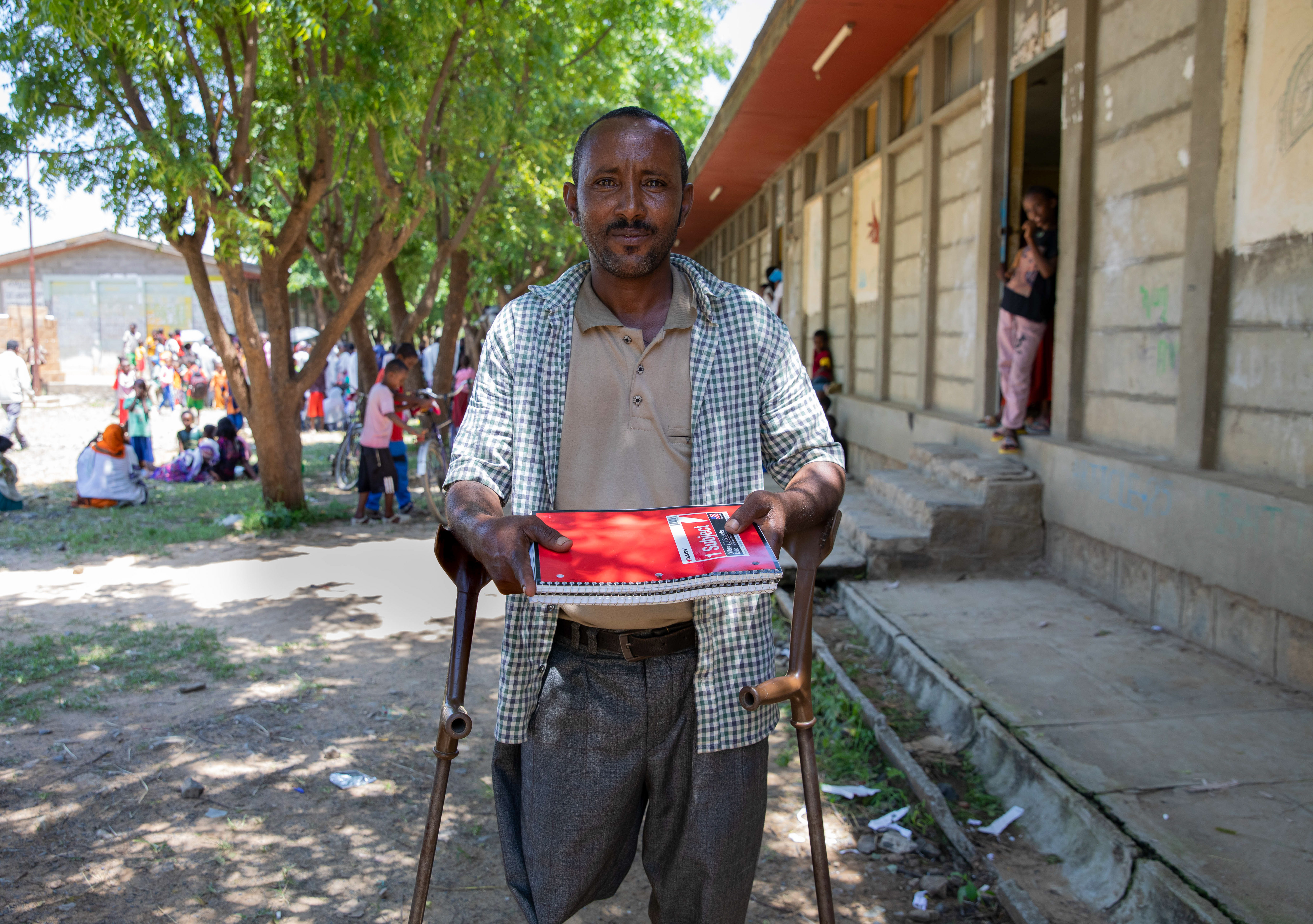 man on crutches without one leg holds school kit