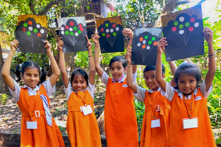 Five school girls hold up their art work.