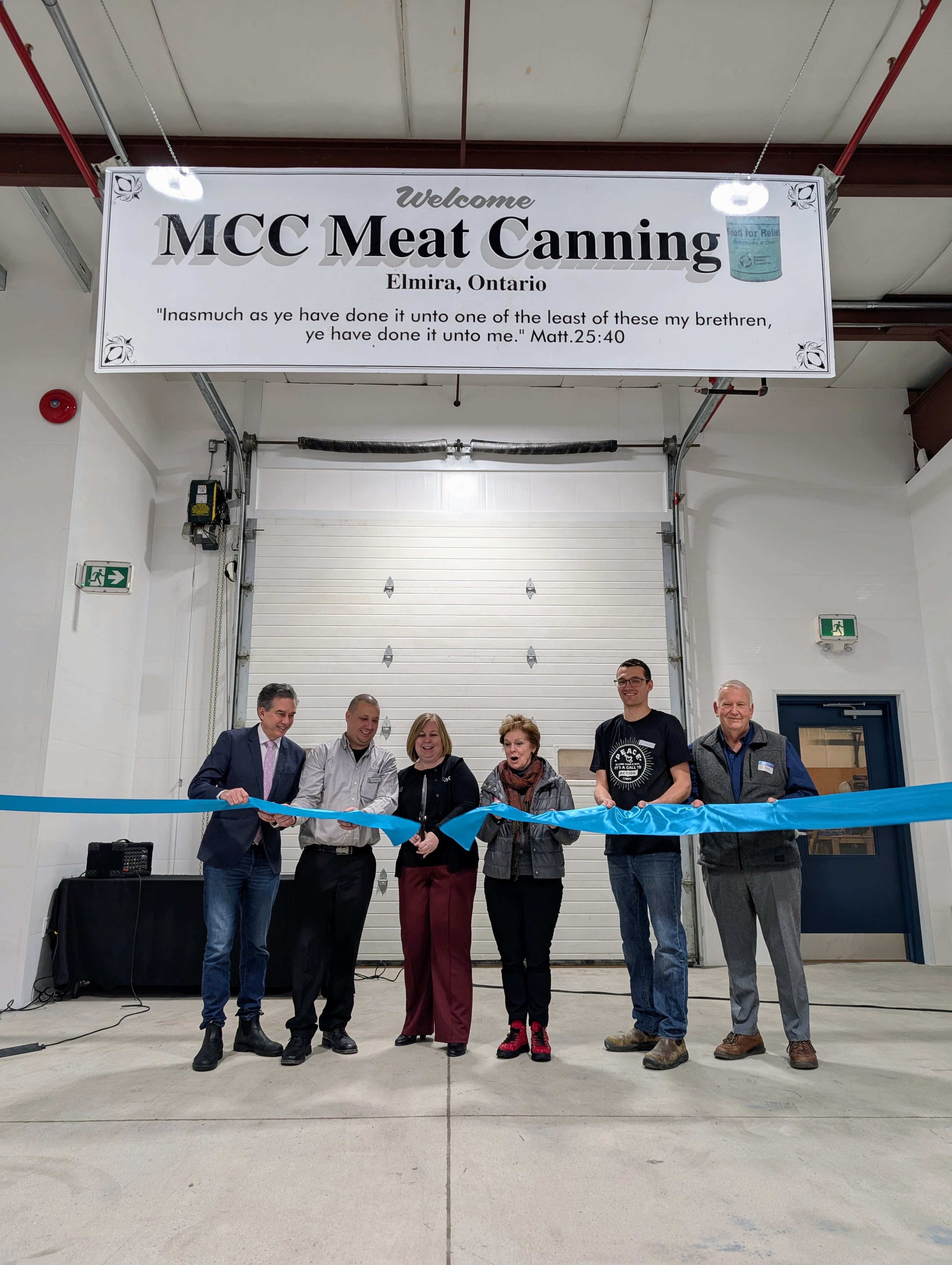 A group of people cut a ribbon signifying the opening of the MCC Meat Cannery