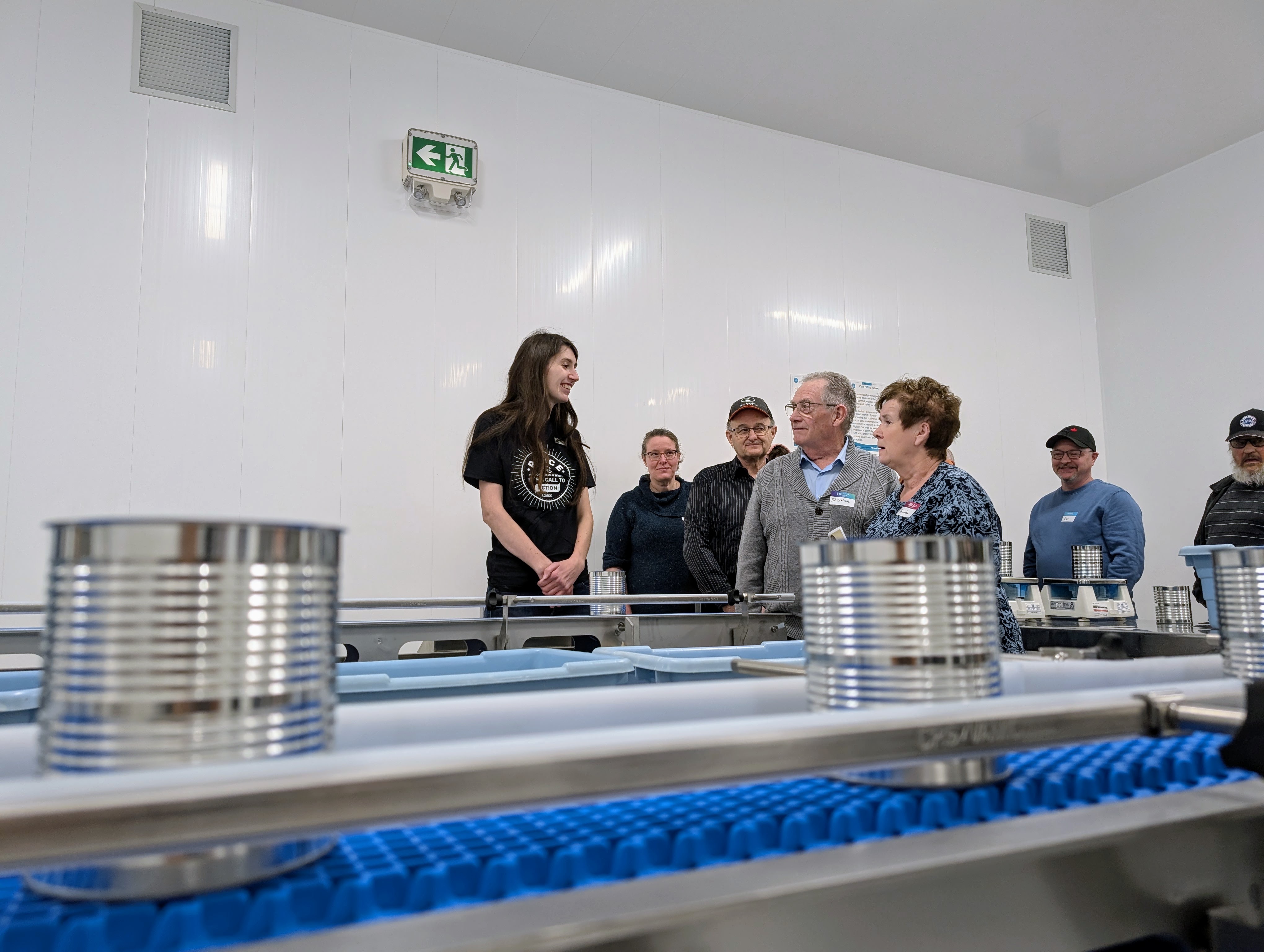 A woman explains how a piece of equipment in the MCC Meat Cannery works.