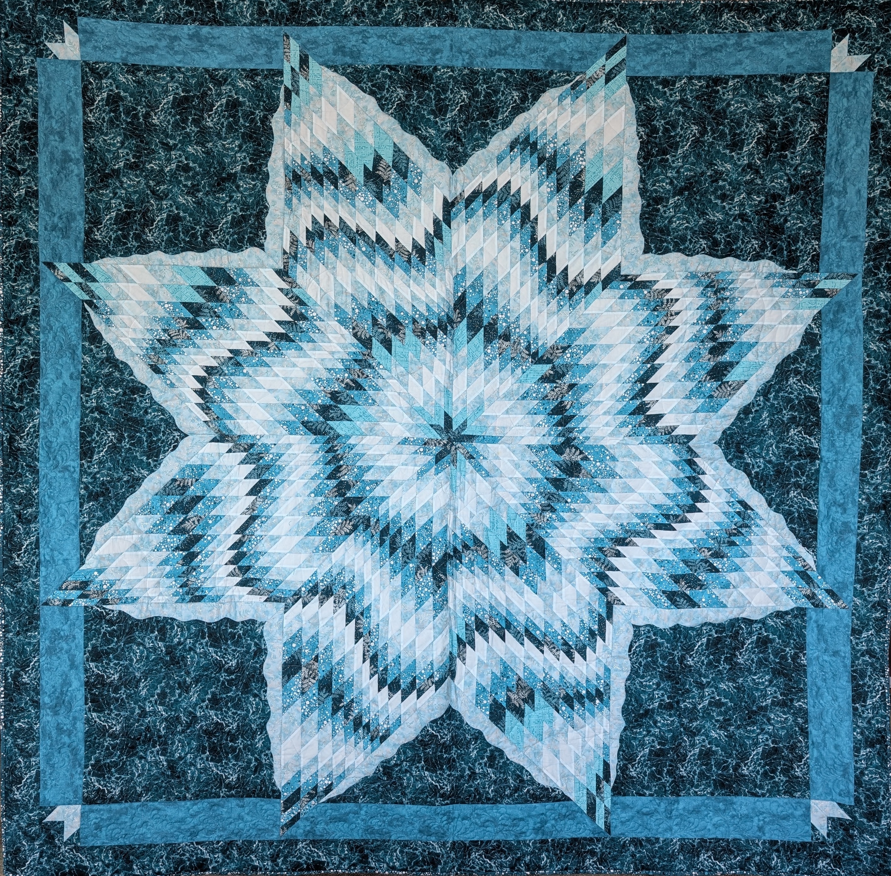 A blue quilt in a star pattern with waves woven between the points.