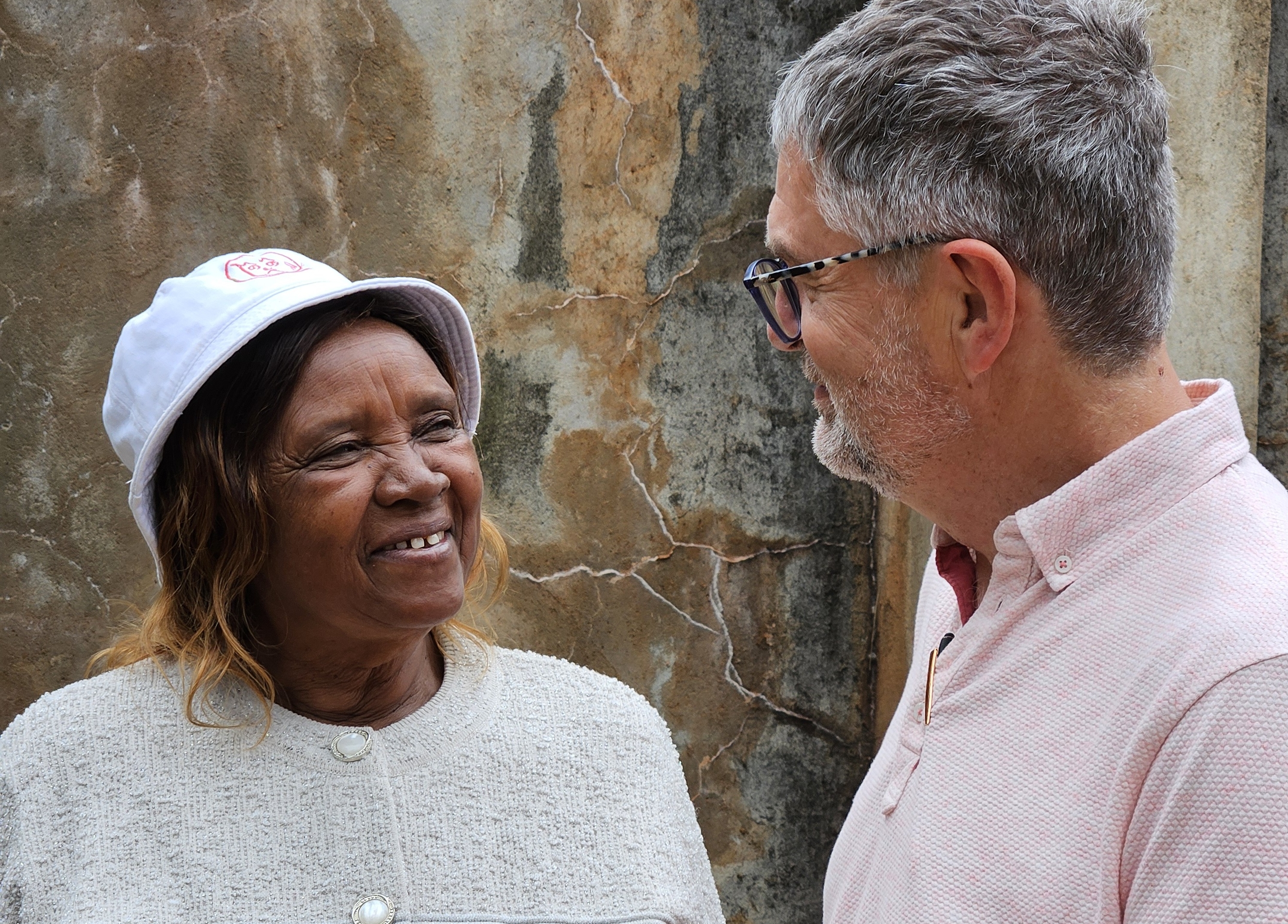 woman in white hat looking in the face of taller man with glasses