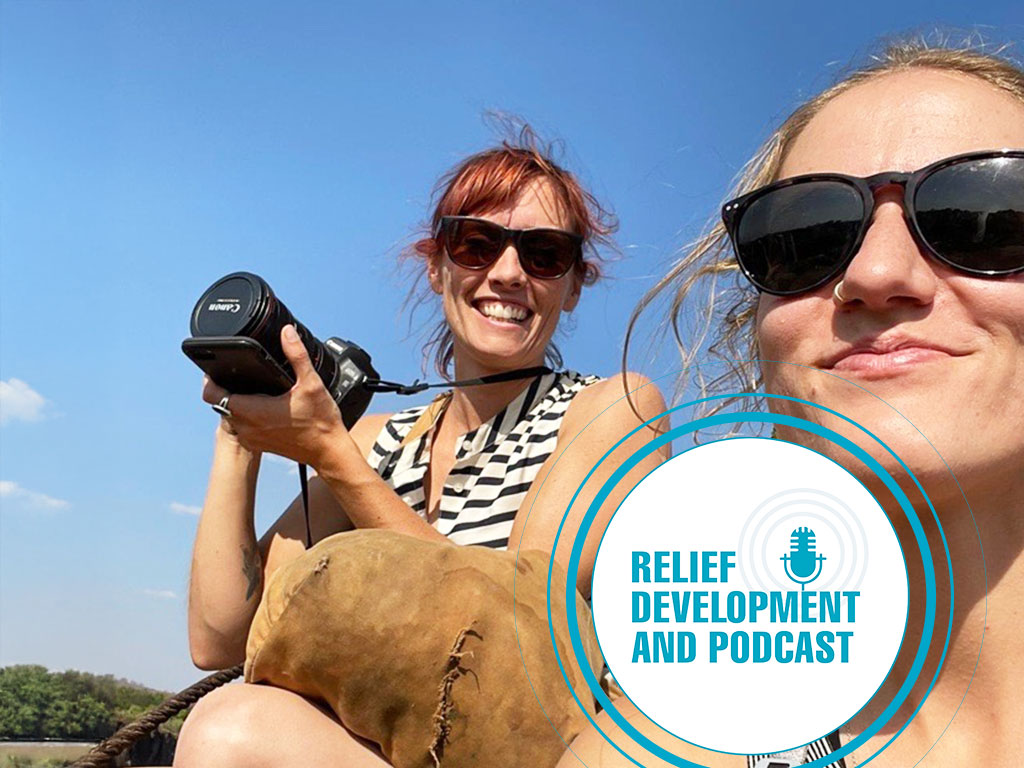 two women smiling, one is holding a camera