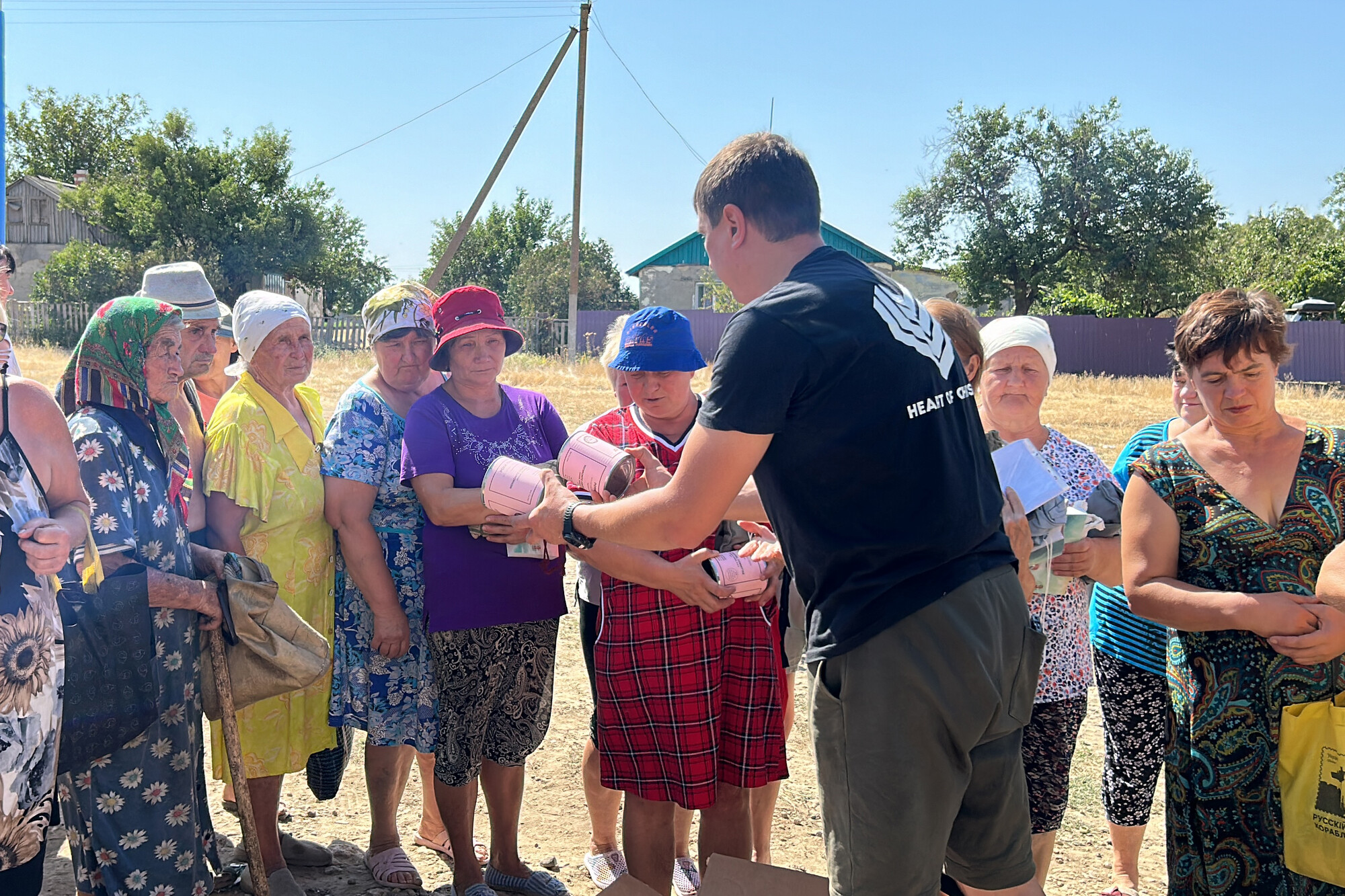 Man handing cans of meat to women standing in a line