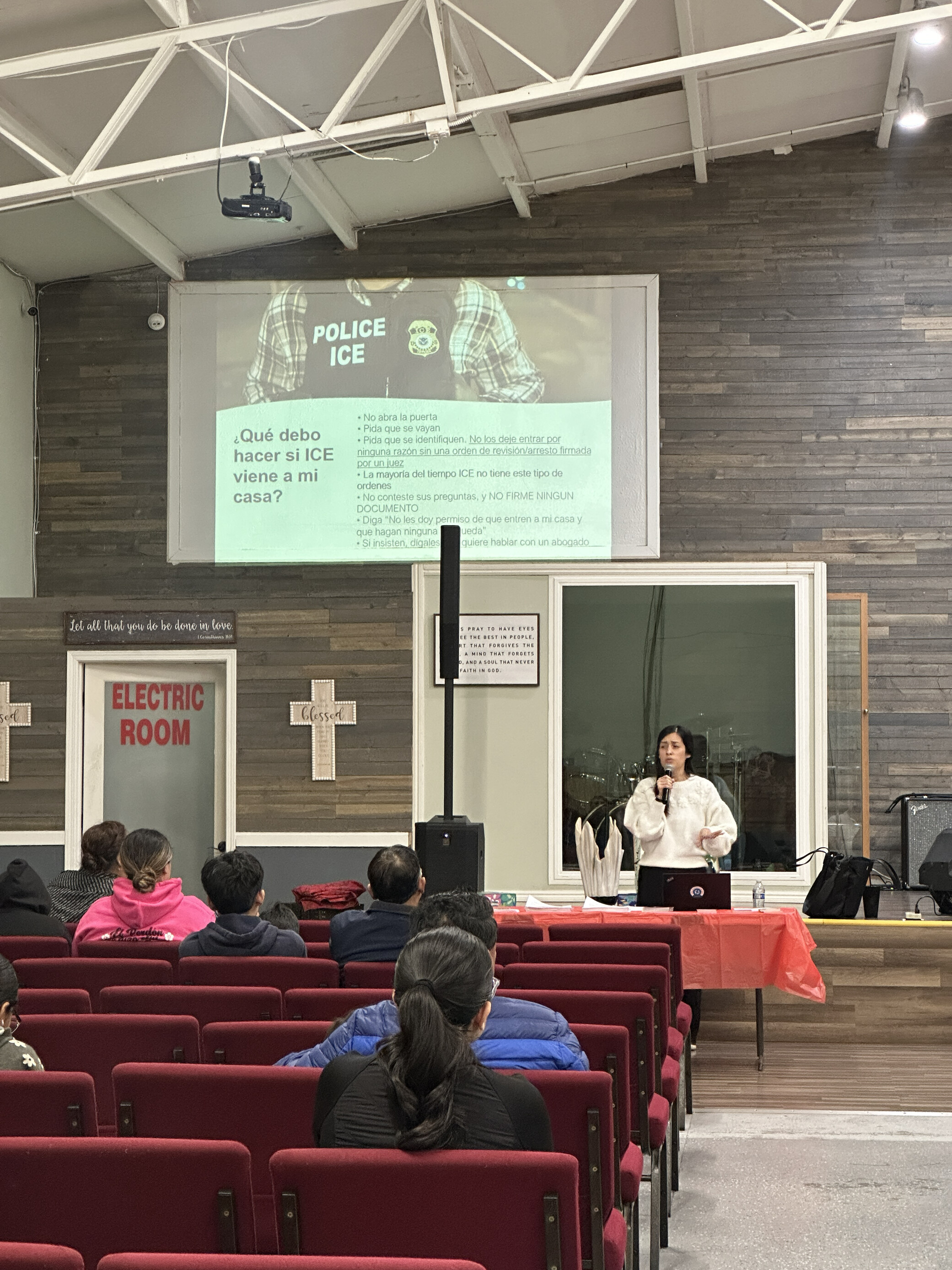 woman in front of church talking to audience with powerpoint on screen above her