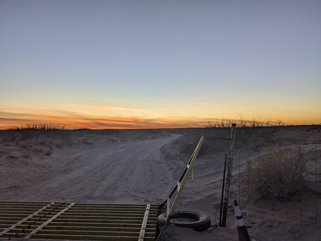 Sunset over desert with cattle gate and fence