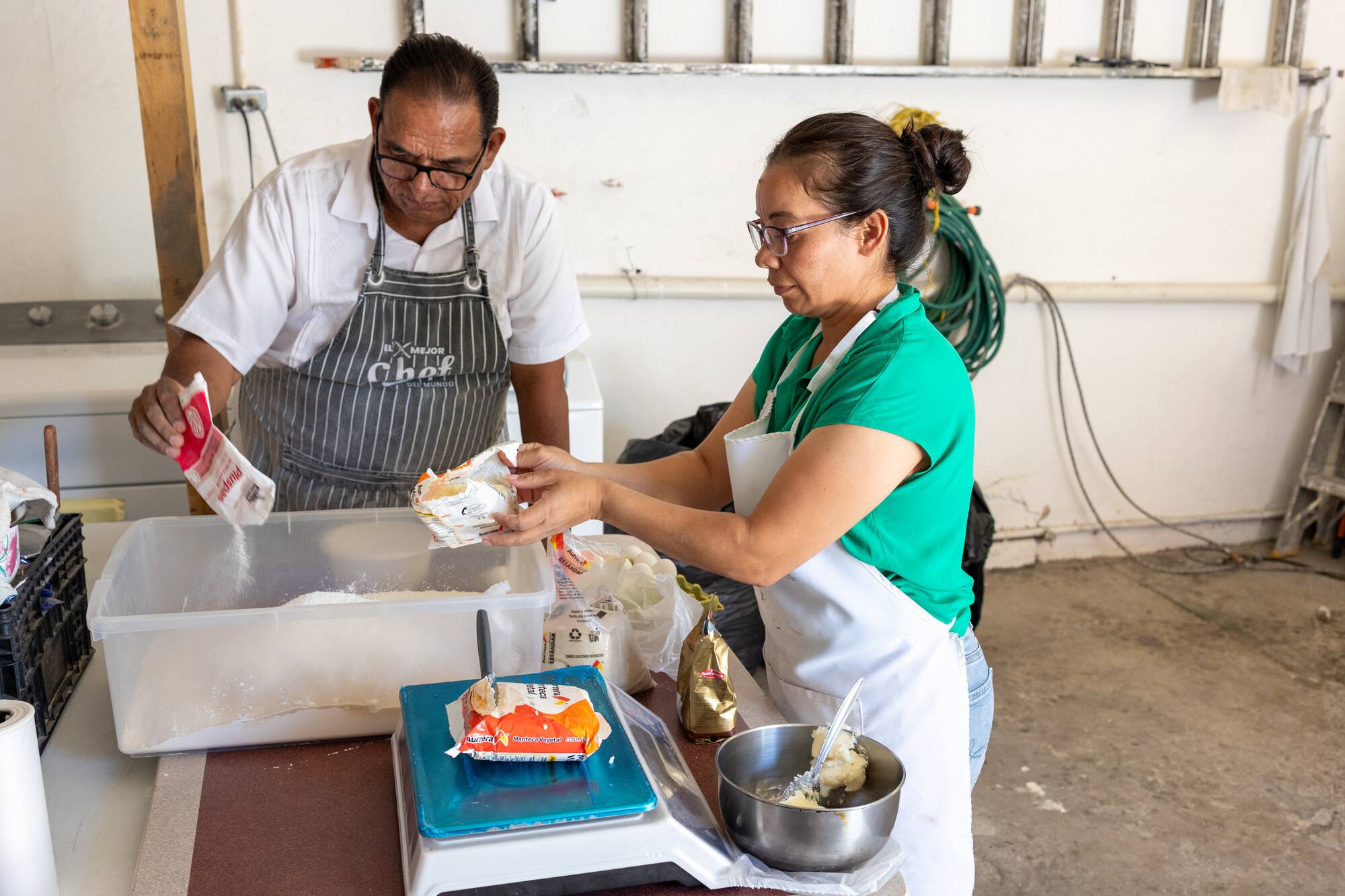 Pastor Roman Dominguez, left, and volunteer Consuelo Martinez make donuts to raise money for the migrant shelter where they work. Oasis del Migrante (Migrant Oasis) shelter is part of Somos Uno Por Ju