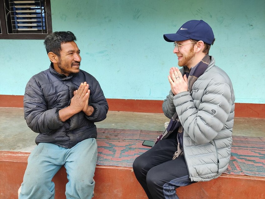 Bhakta Bahadur Karki, a vegetable, fruit and grains farmer, and Evan Strong, an MCC SALT 2022-2023 participant, exchanging a greeting before beginning an interview in Ikudol, Nepal.