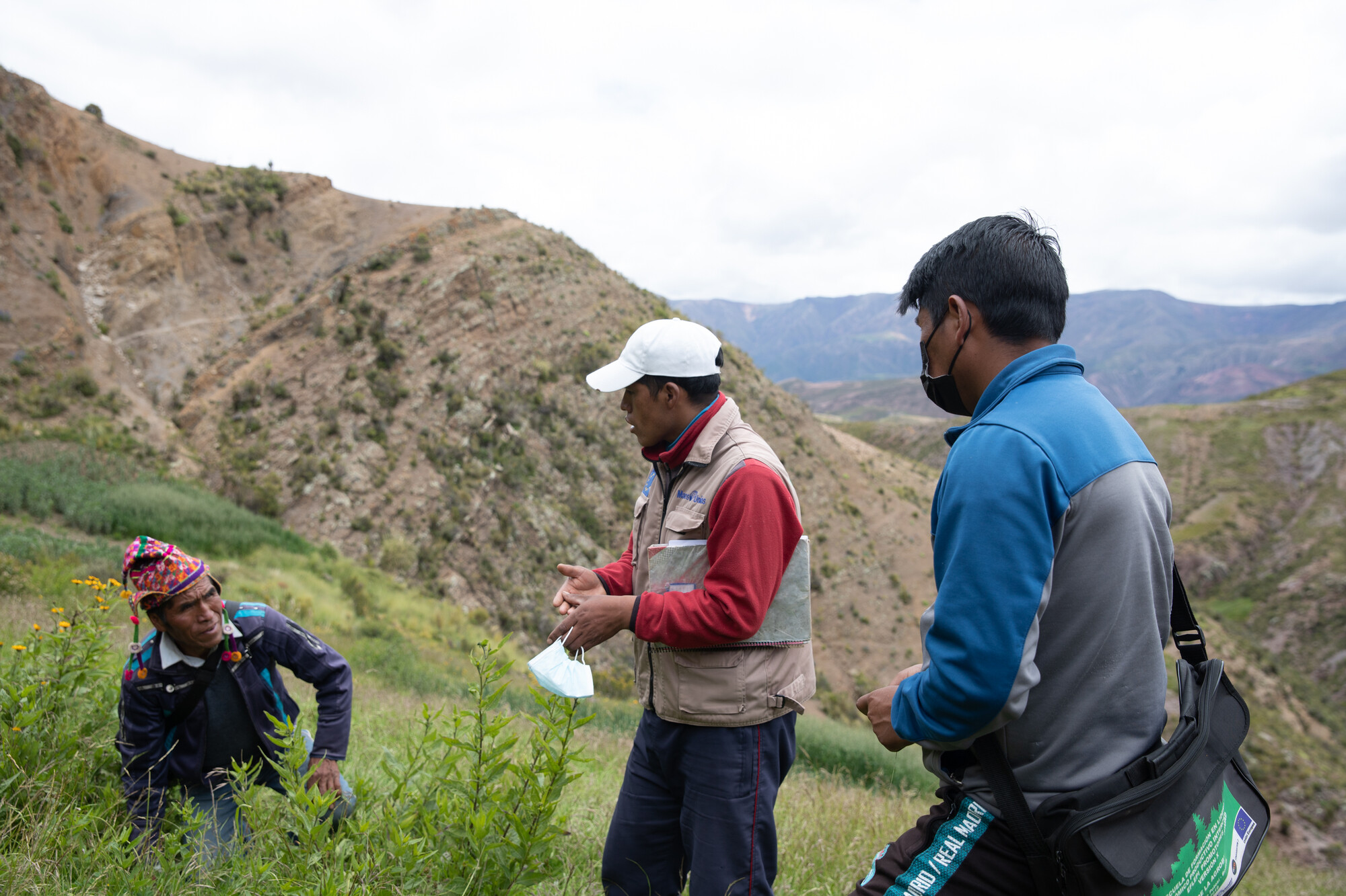 Gabriel Acarapi Chuca (middle) of MCC partner PRODII speaks with project participant Segundino Ignacio during a community visit with staff of MCC Bolivia and PRODII. Heraclio Mateo stands right.