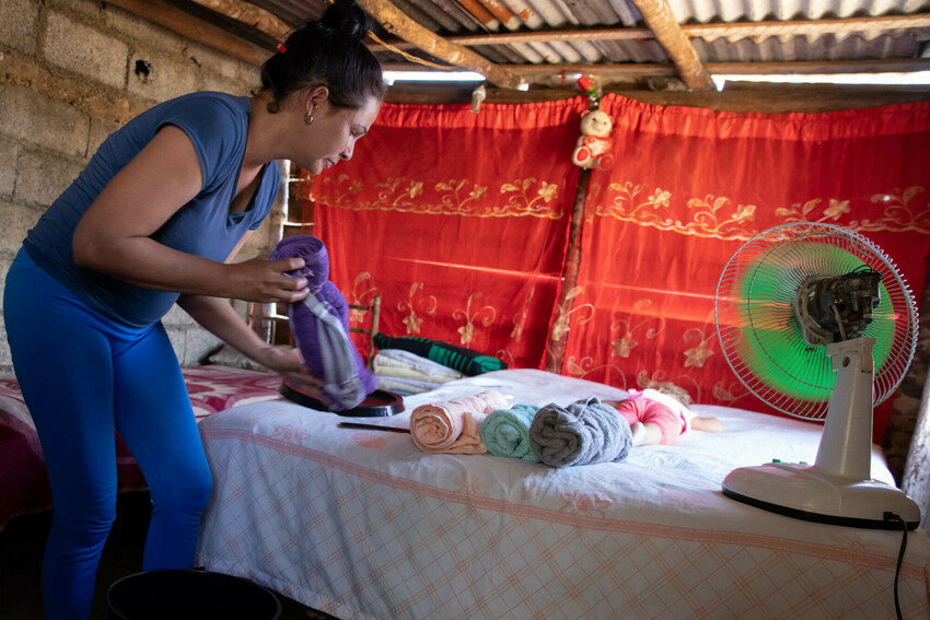 Ana Malena Cruz Montero unpacks items from an MCC relief kit in the small outbuilding on her property where her family is sleeping after Hurricane Ian damaged the roof of her house in 2022. She receiv