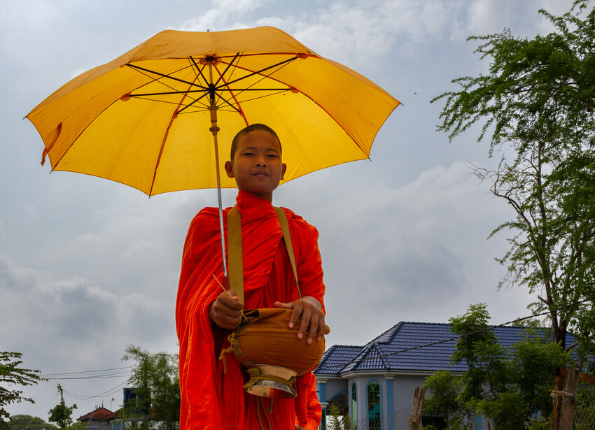 Ry Veasna, 17, a monk from the Snae Ben Pagoda in Mesang district, Cambodia, walks through Snae Ben to collect offerings of food and money from local inhabitants. This is a daily morning practice for