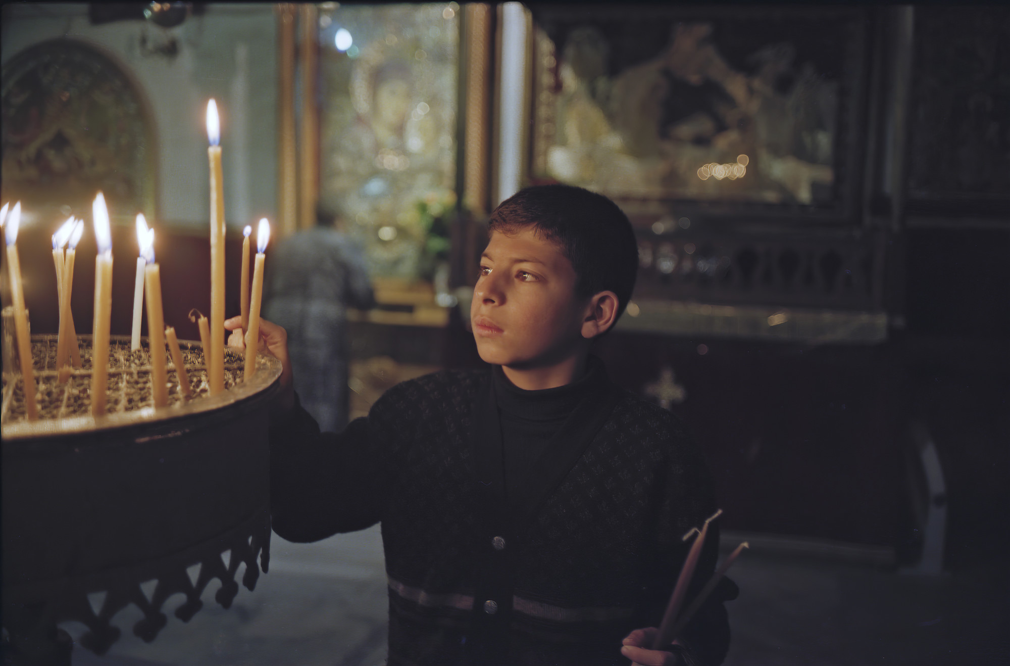 Milade Thalgieh (pictured in 2001) lights a candle in Bethlehem’s Church of the Nativity, West Bank, Palestine weeks after his brother Johnny, 17, who wanted to be a priest, was shot and killed while