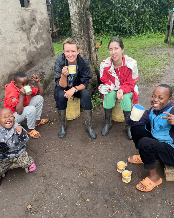 Two young adults sit holding mugs with three children.