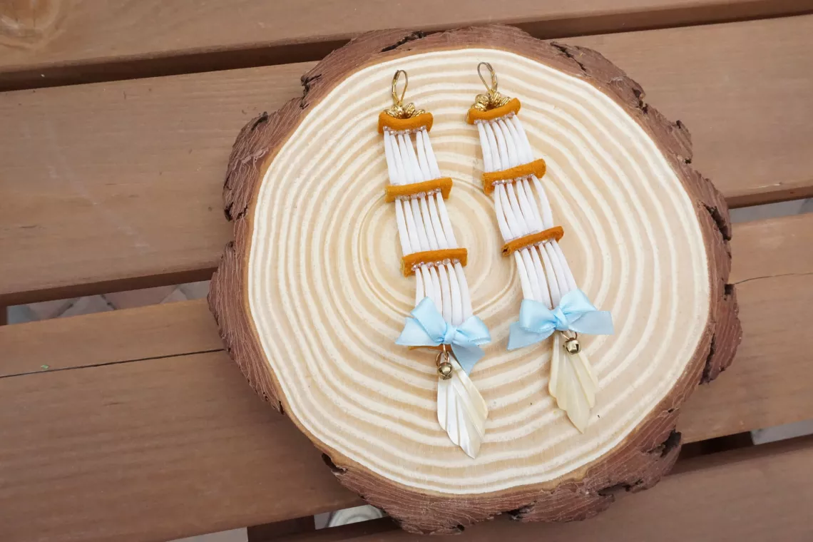 Tro-color earrings displayed on a log cross-section.