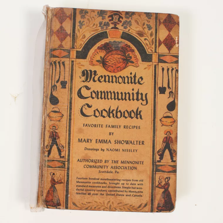 Cover of The Mennonite Community Cookbook. It is yellowed with age.