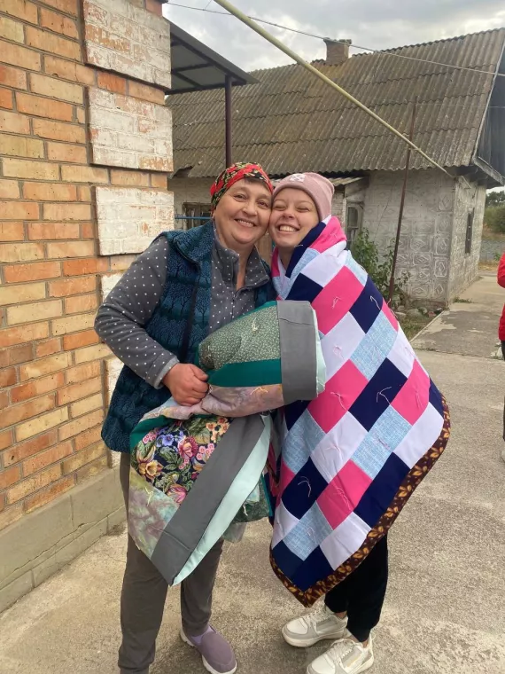 Two beneficiaries in Ukraine are wrapped up in comforters made by MCC volunteers. 