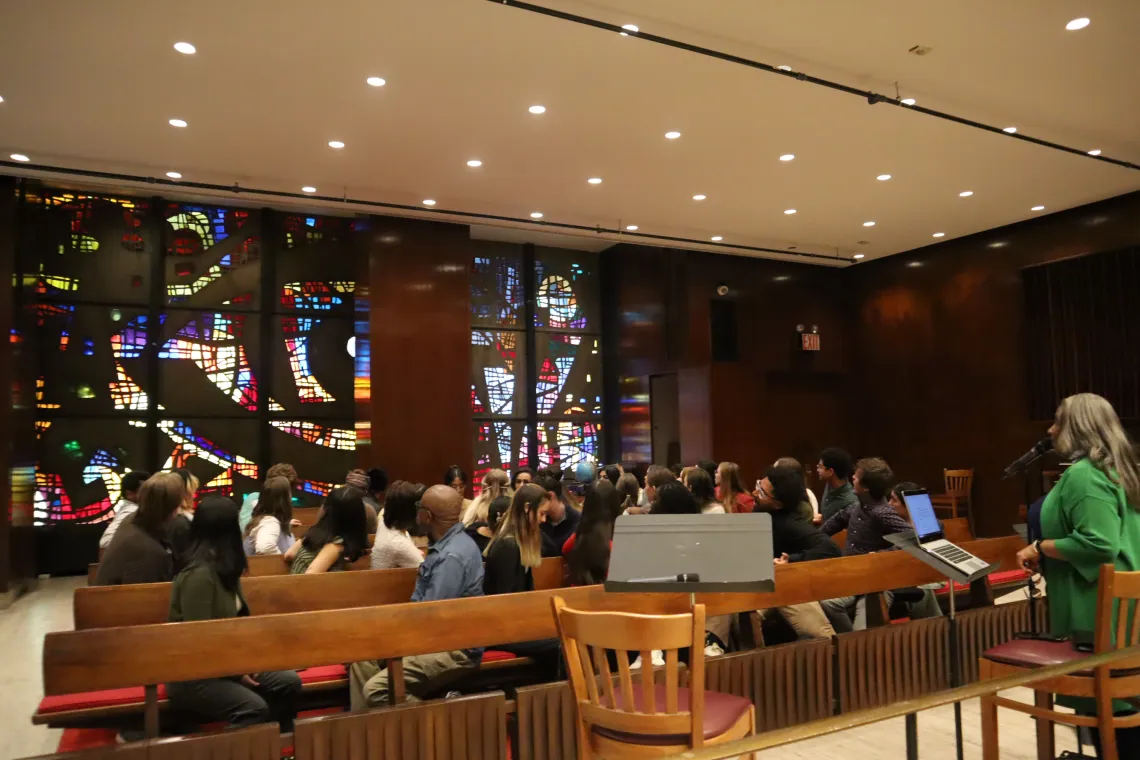 A group of people look at a colorful glass window. 