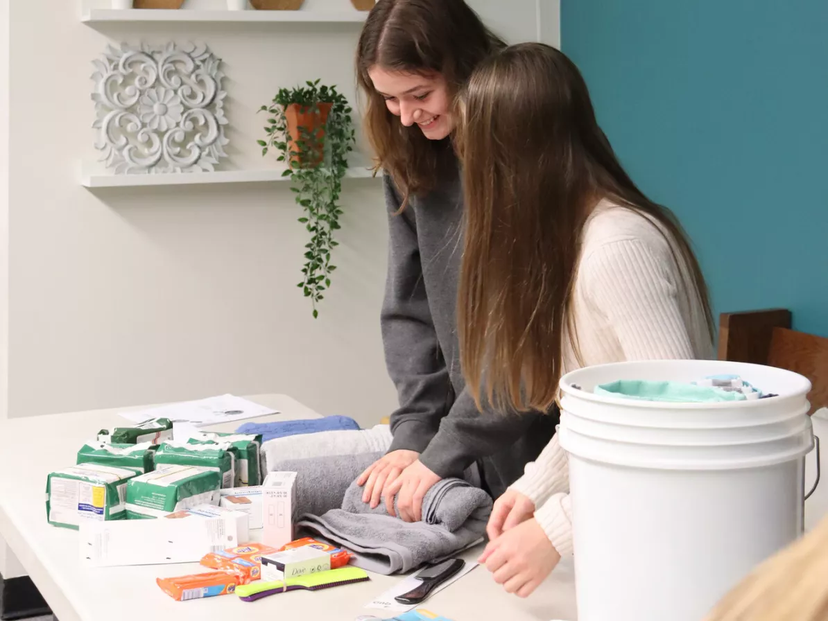 Two girls learn over a table and work with hygiene items