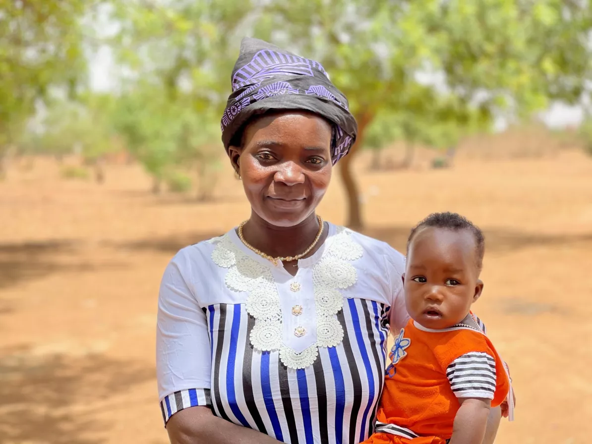 A woman holds her baby and looks at the camera