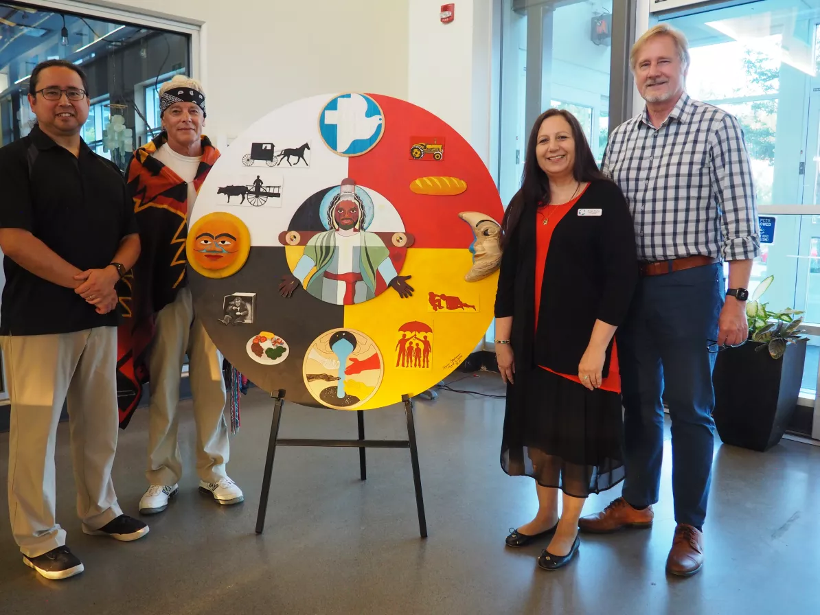 Four people standing next to an art piece