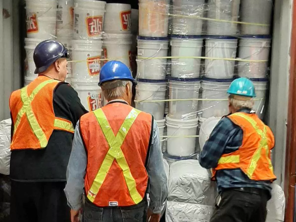 Three men load truck with relief supplies