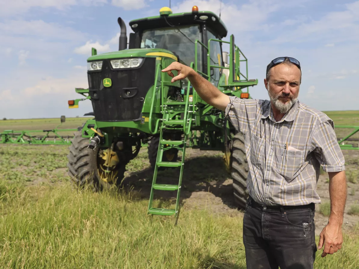 man pointing with tractor behind him