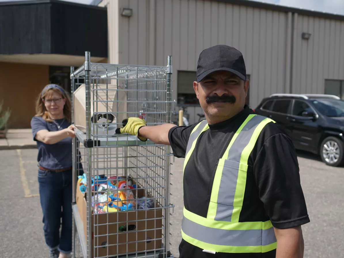 a man and woman move a cart through a parking lot