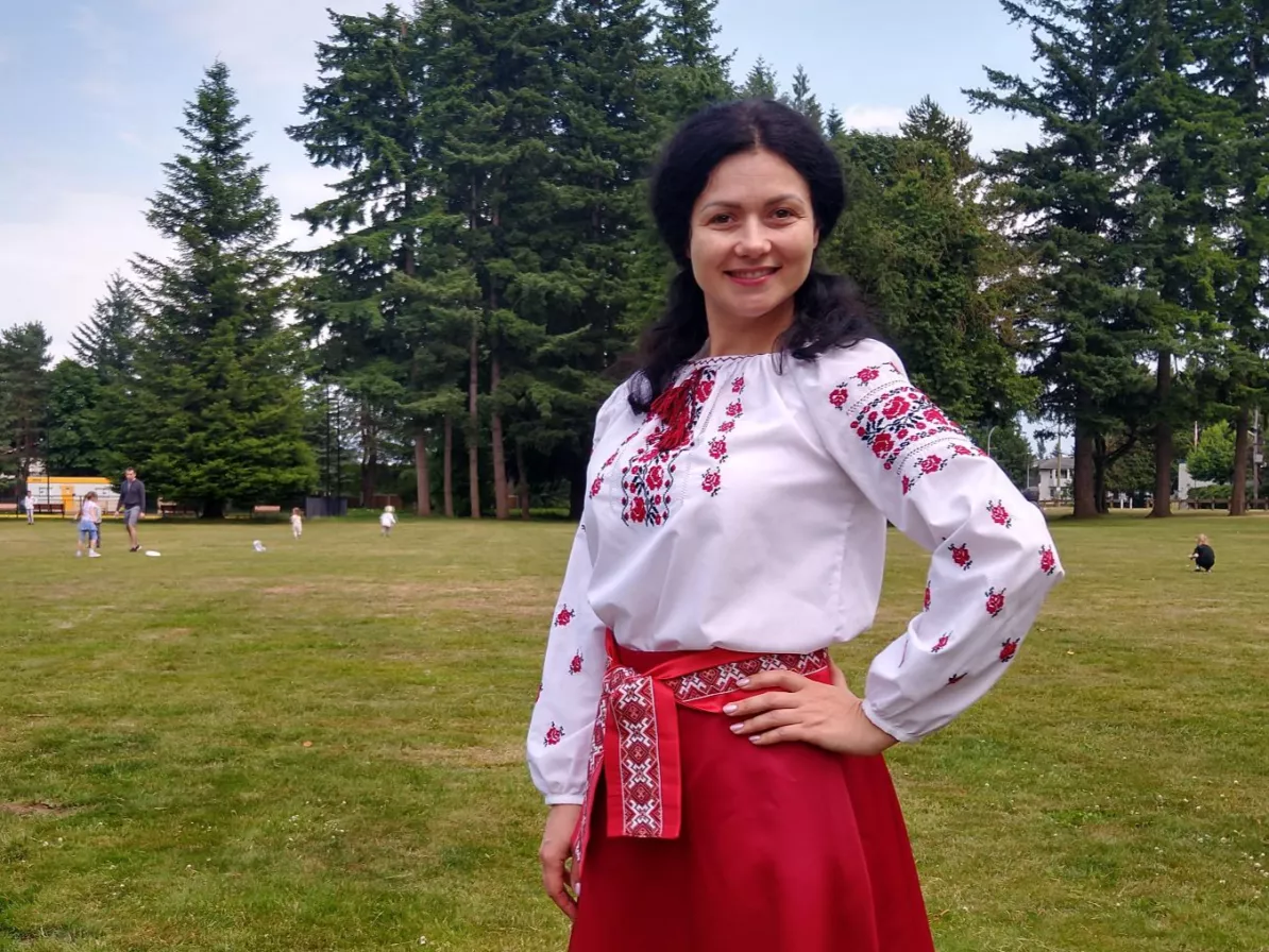 A woman in a field in a red and white traditional Ukrainian outfit