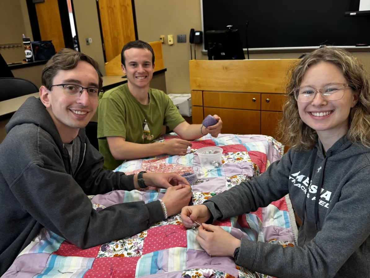 From left to right, Noah Calisti, Ray Truex, and Katie Anthony knot a comforter during Messiah University’s Day of Service.