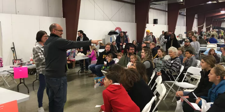 auctioneer pointing to crowd of children at toy auction