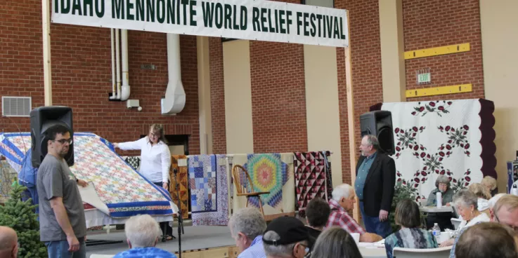  People sitting in audience for quilt auction.