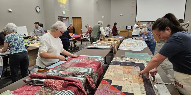 two women trim the edges of comforters 