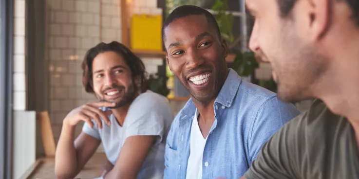 Three men sitting in a row chatting.