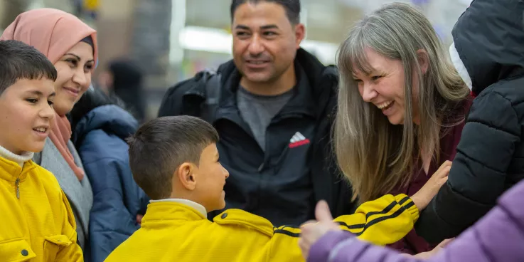 a family of refugees is greeted at the airport by their sponsors