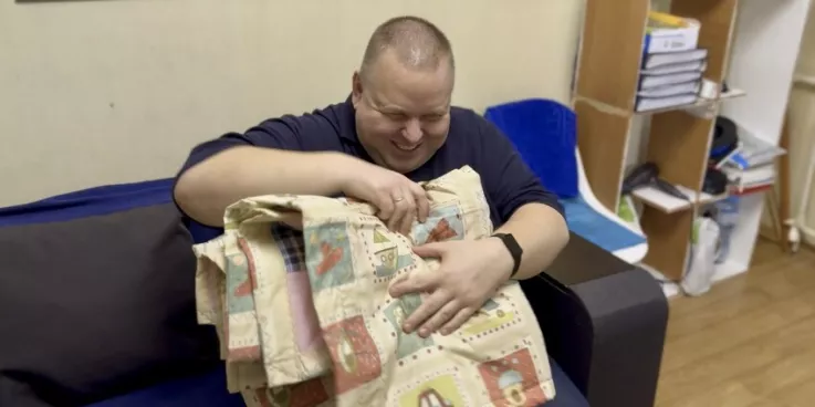 Serhiy,* who is blind,  examines the new MCC comforter he just received from MCC partner New Life in Nikopol, Ukraine.*Family name is withheld for security reasons.