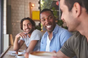 Three men sitting in a row chatting.