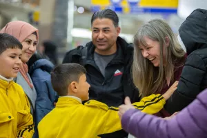 a family of refugees is greeted at the airport by their sponsors