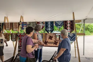 Women admiring quilts on a rack